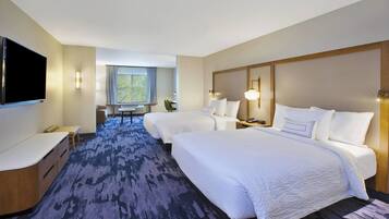A hotel room with two beds, a desk, a flat-screen TV, and a window with a view.
