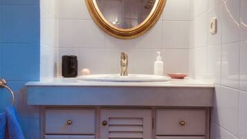 A bathroom with a white vanity, a gold-framed mirror, and a blue towel.
