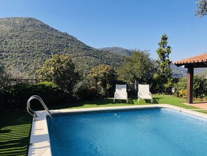 Een seizoensgebonden buitenzwembad en ligstoelen