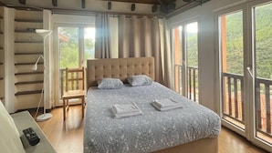 Une chambre avec un grand lit, une chaise, un bureau et un balcon avec vue.