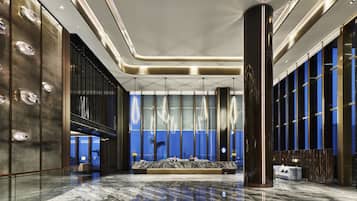 A modern lobby with a marble floor, large columns, and a seating area with a view of the city.