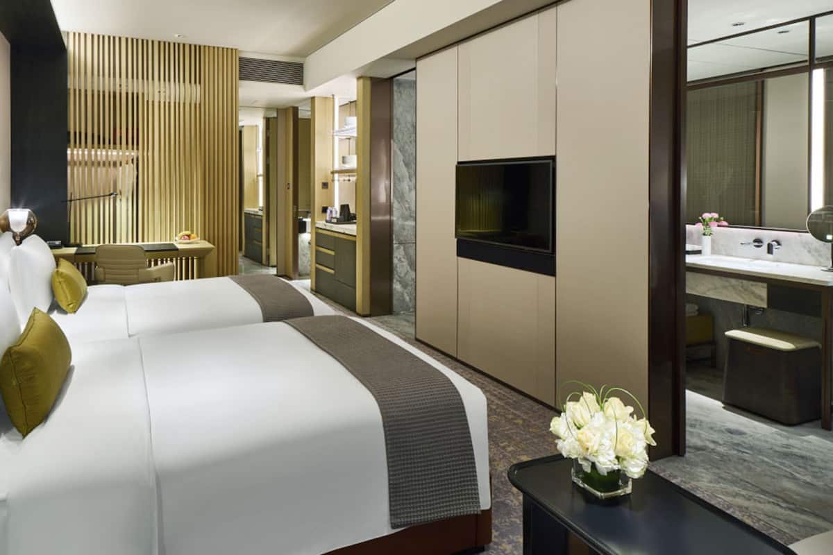 A hotel room with a large bed, a desk, a TV, and a bathroom.
