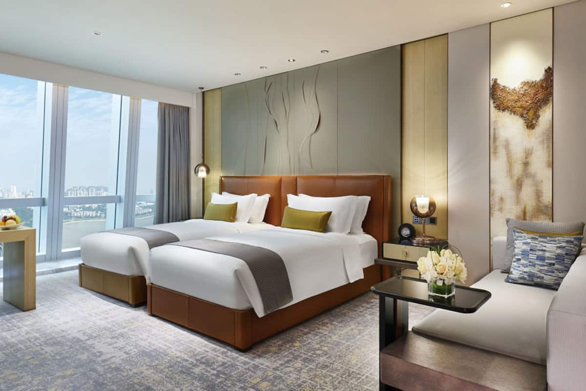 A modern hotel room with a large bed, a desk, and a sofa.