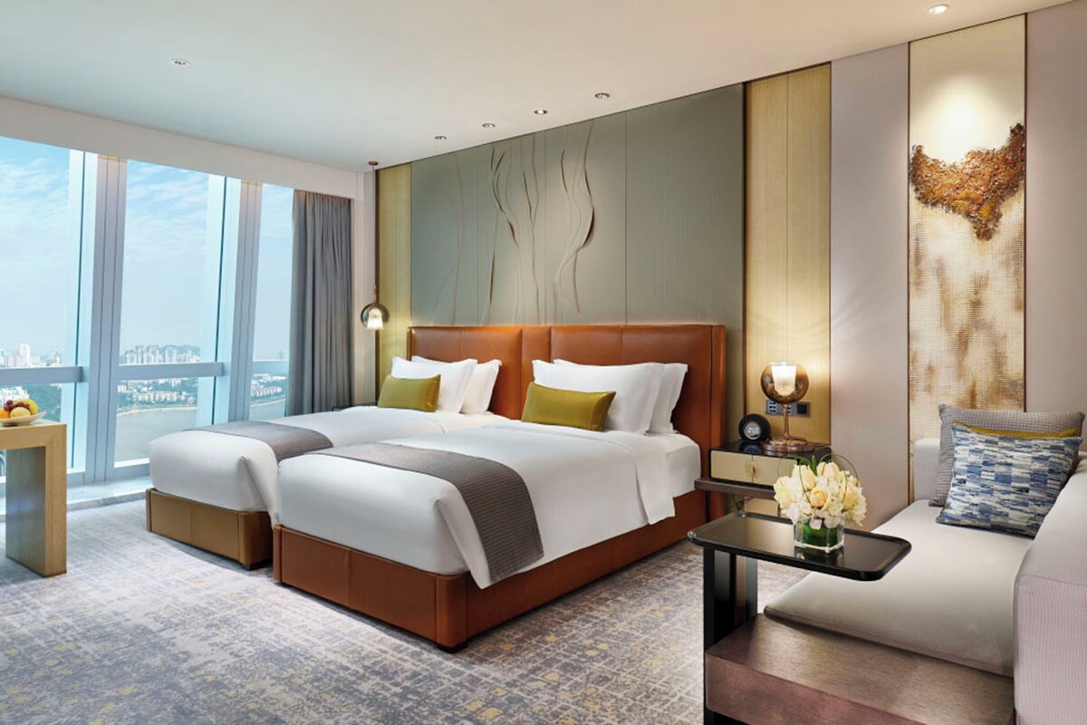 Una habitación de hotel con una cama grande, un escritorio, una silla y vistas a la ciudad.