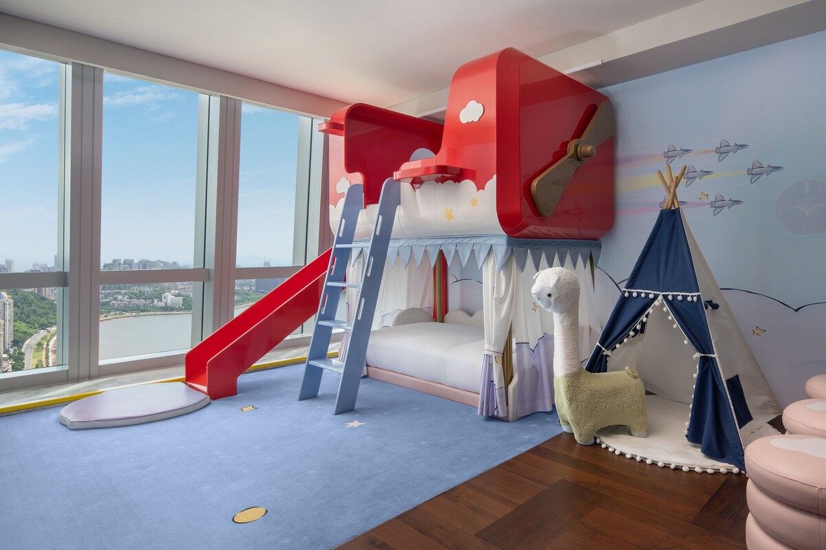 Habitación infantil con literas, un tobogán, una tienda de campaña y vistas a la ciudad.
