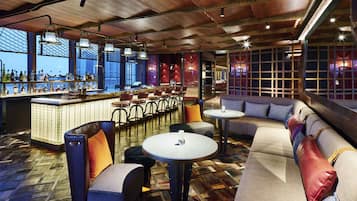 A bar area with a long counter, multiple chairs, and a sofa.