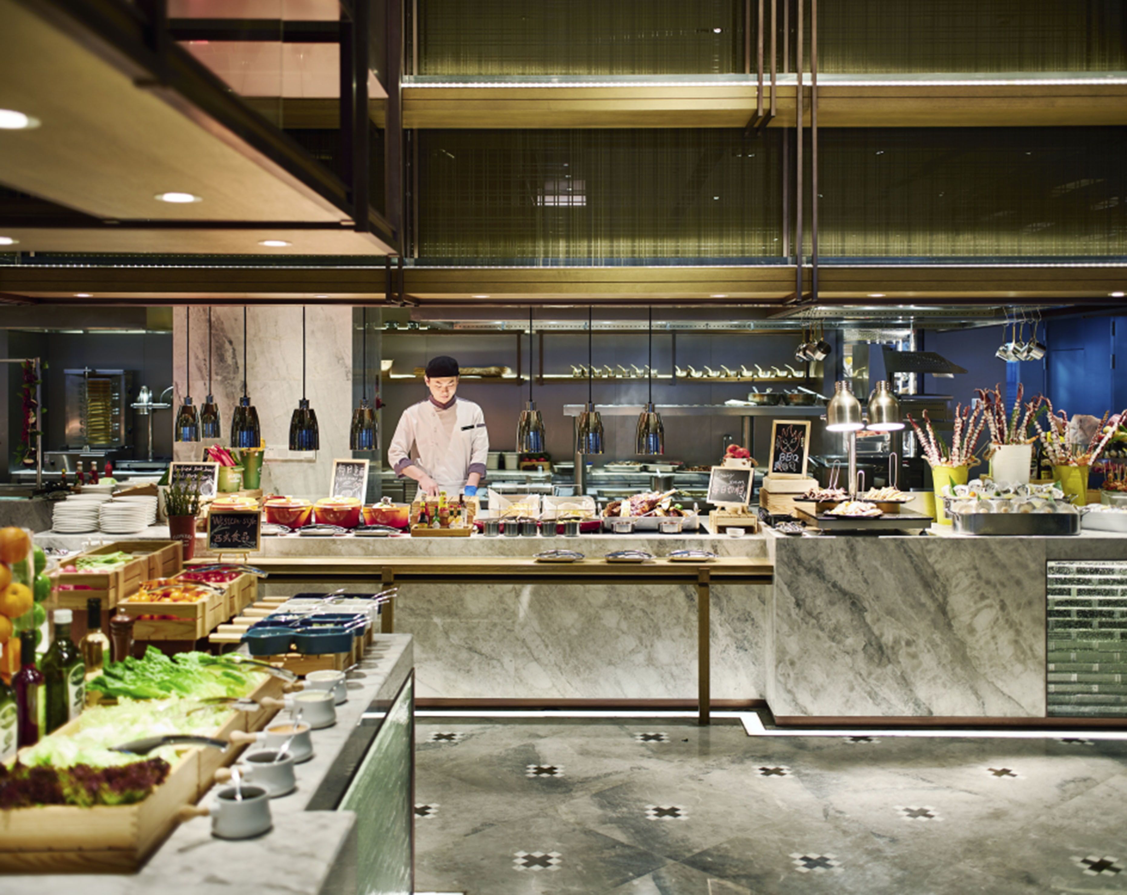 A modern restaurant with a chef preparing food, a variety of dishes displayed, and a clean, contemporary interior.