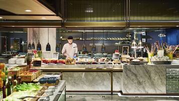 A modern restaurant with a chef preparing food, a variety of dishes displayed, and a clean, contemporary interior.
