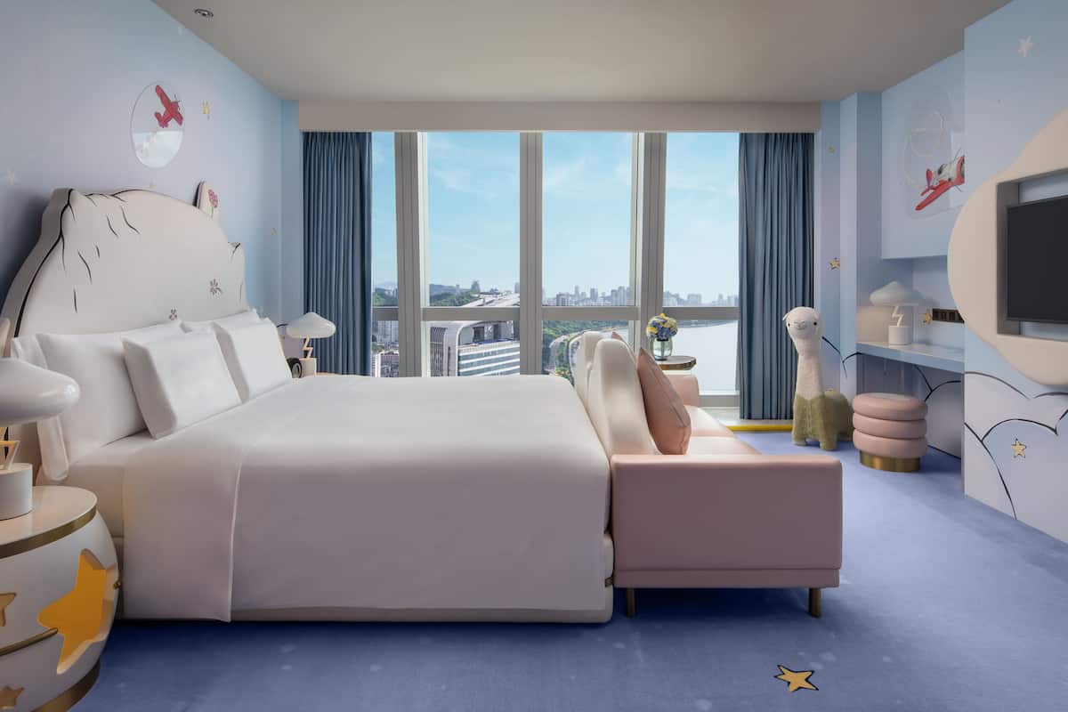 A modern hotel room with a large bed, a TV, and a city view.