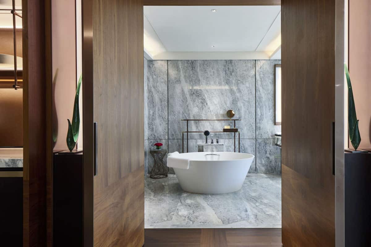 A modern bathroom with a freestanding bathtub, marble walls, and a minimalist design.