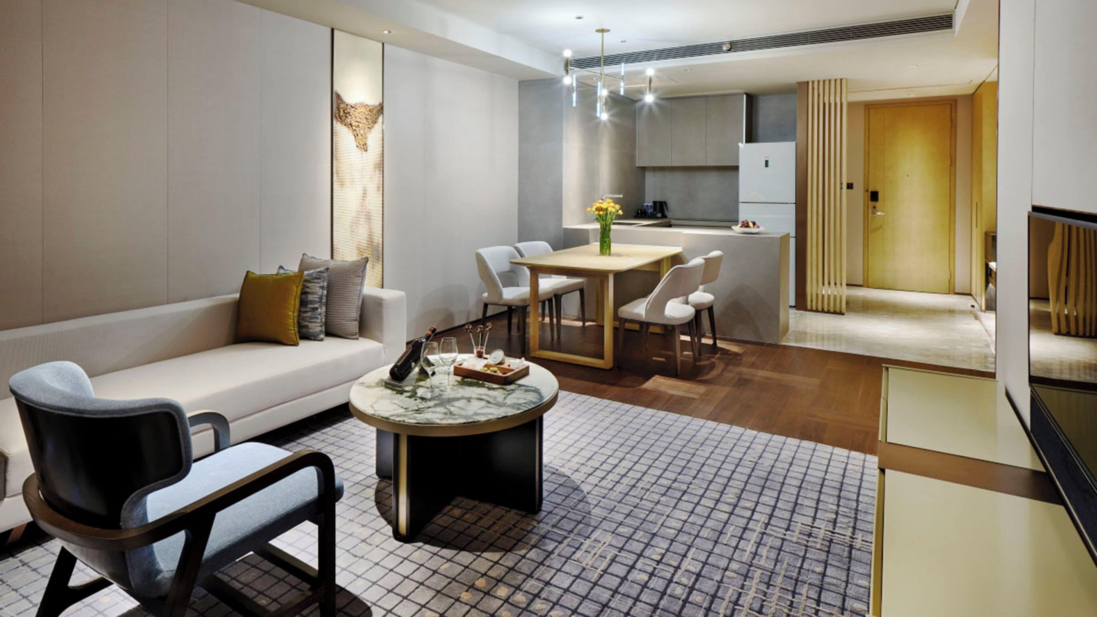 A modern living room with a sofa, a coffee table, and a dining area with chairs.