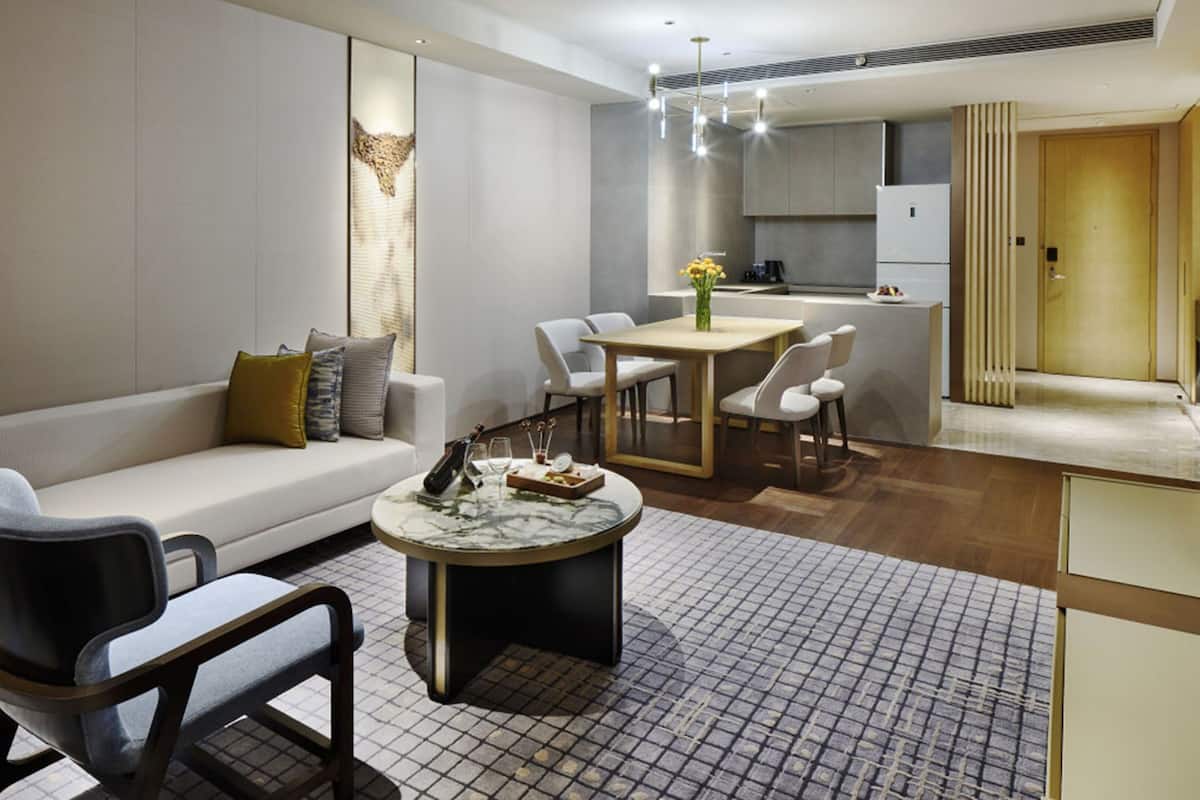 A modern living room with a sofa, a coffee table, and a dining area with chairs and a table.