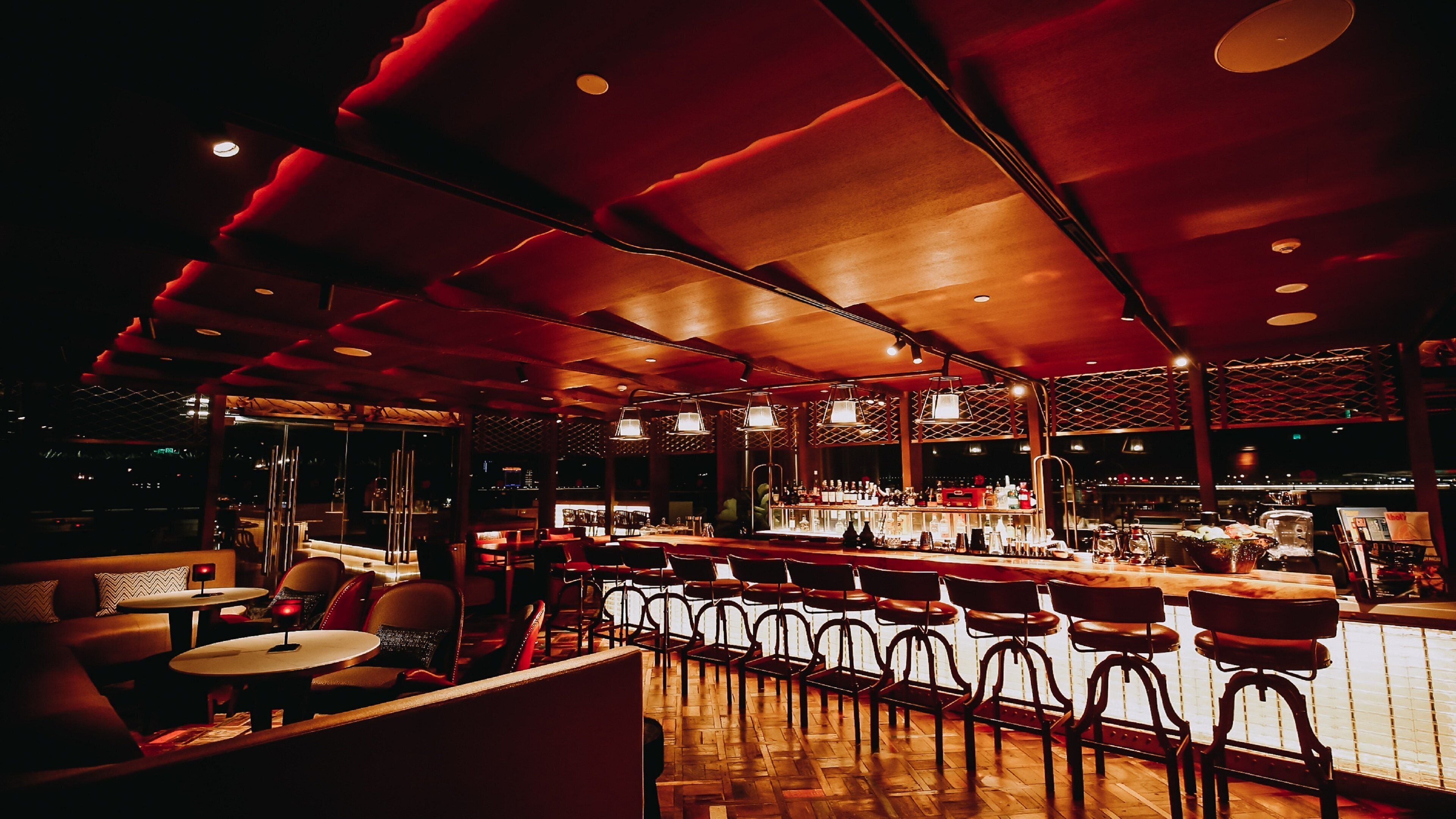 A bar area with wooden flooring, bar stools, and a bar counter.