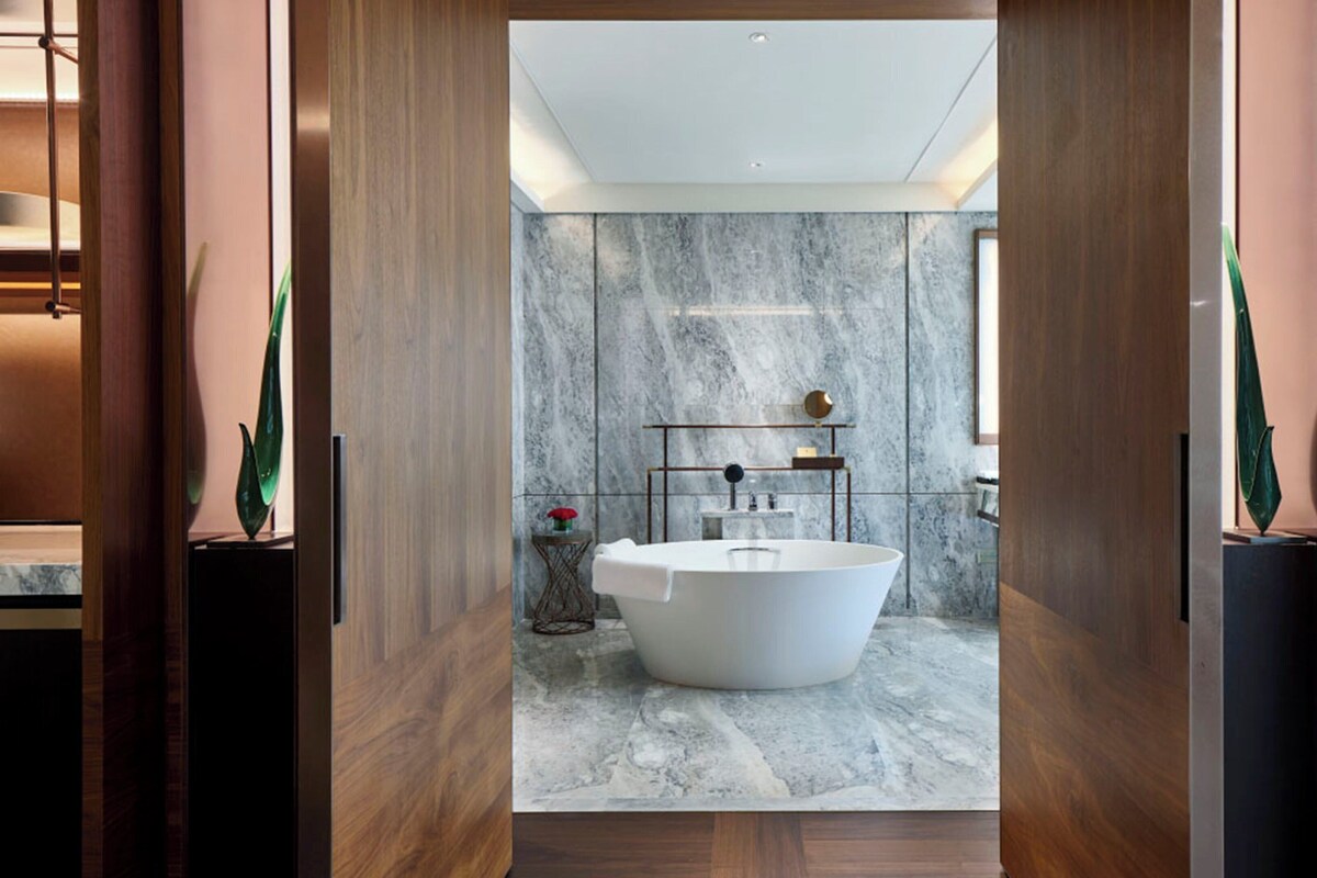 Un baño moderno con una bañera independiente, paredes de mármol y un diseño minimalista.