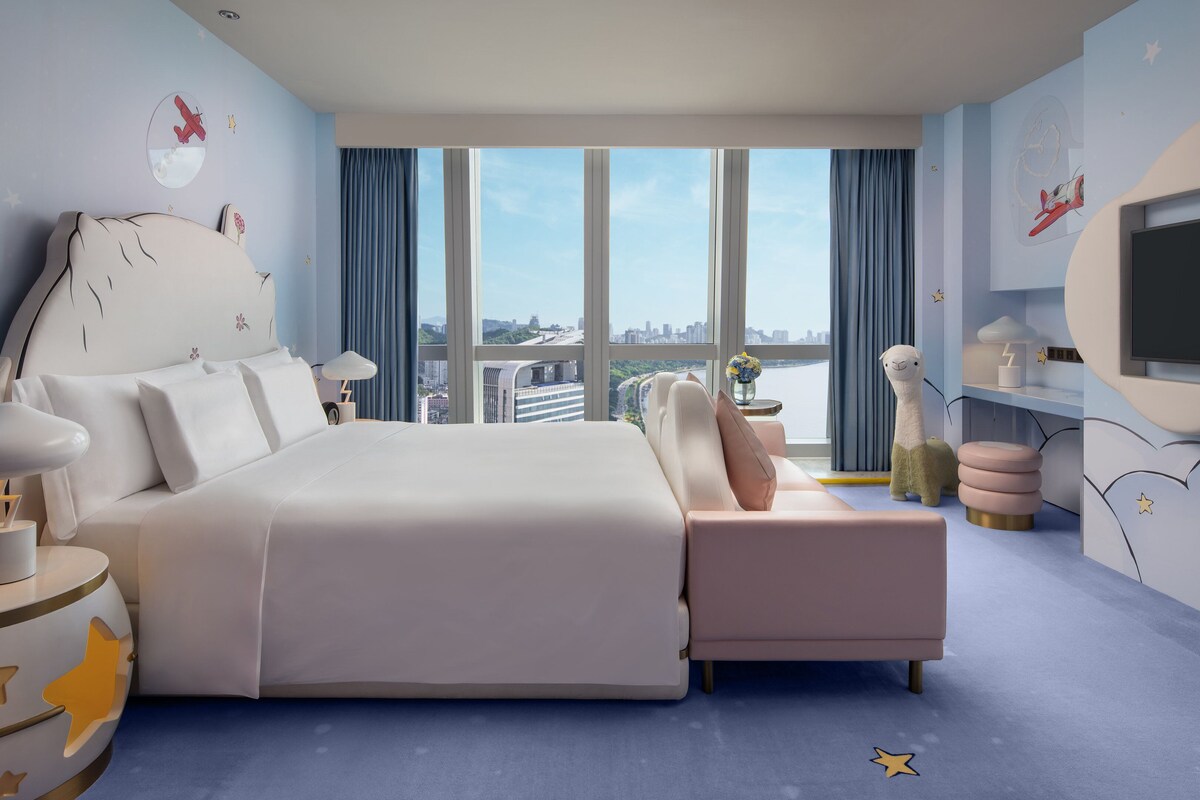 Una habitación de hotel moderna con una cama grande, televisión y vistas a la ciudad.