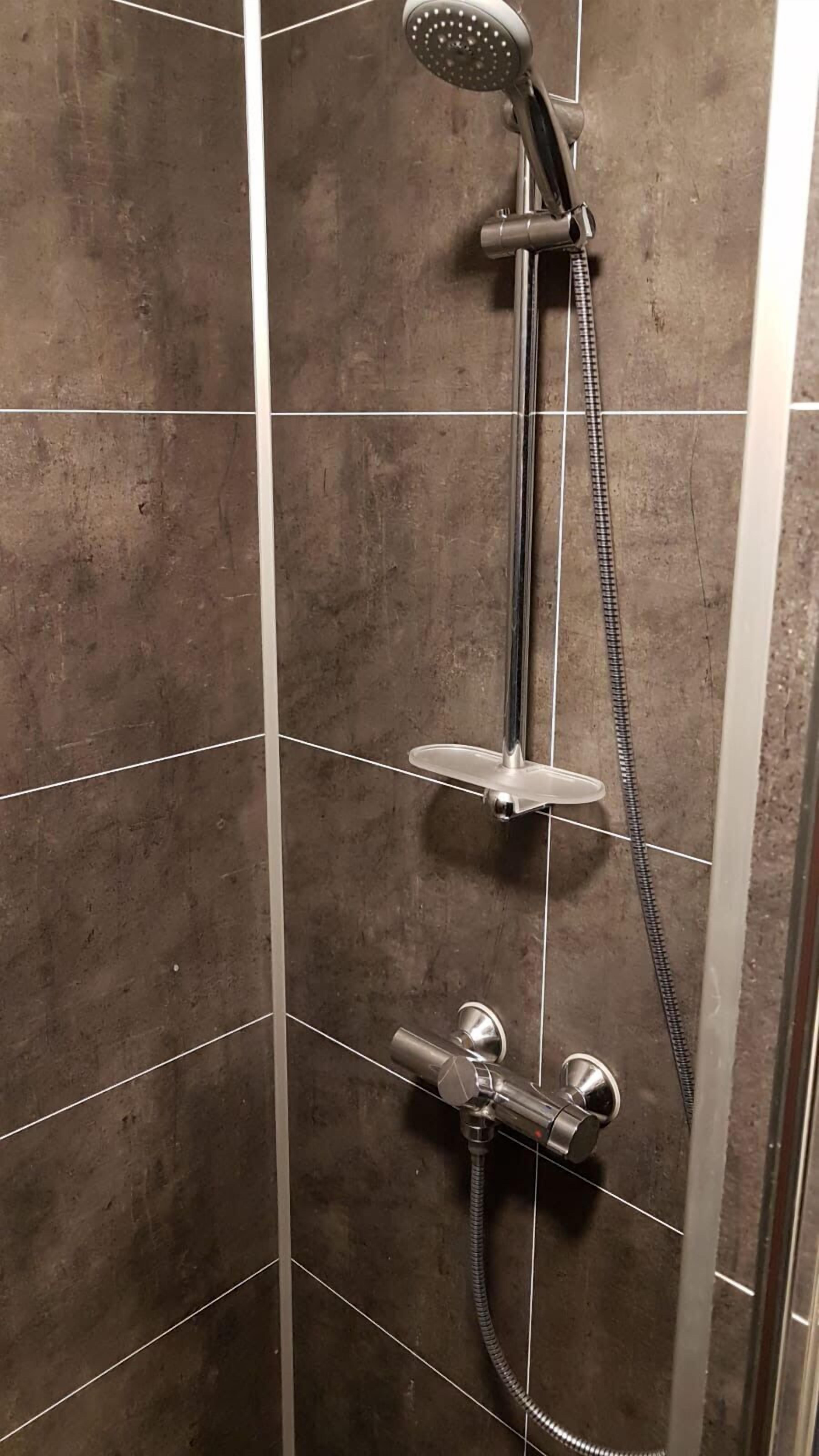 A shower with a handheld showerhead, a handheld showerhead, and a handheld showerhead.