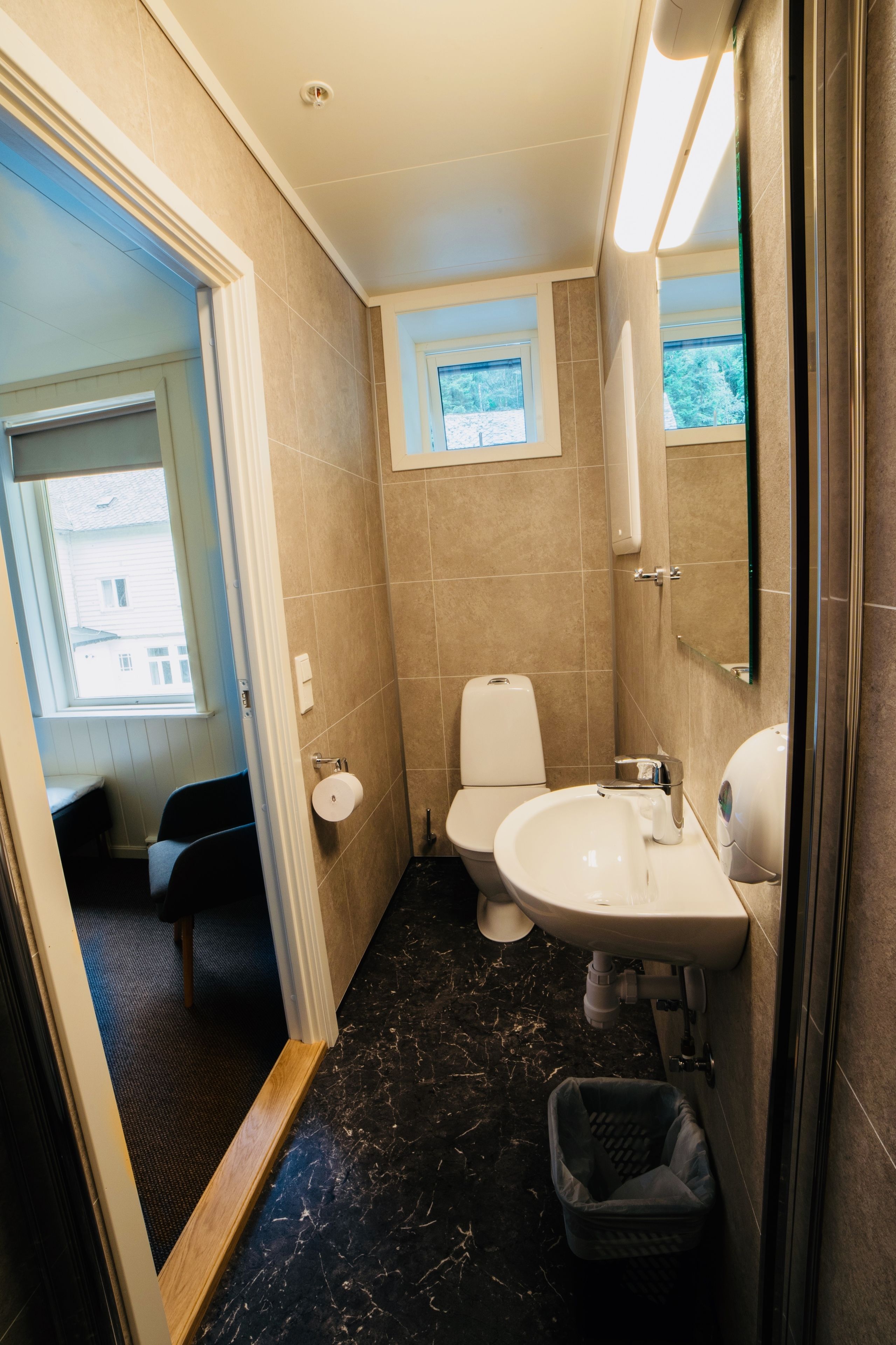 A compact bathroom with a toilet, sink, and window.