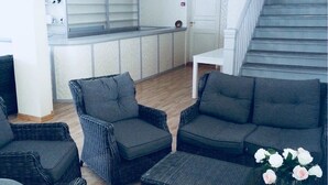 Un salon moderne avec des meubles en osier, un coin cuisine et un escalier.