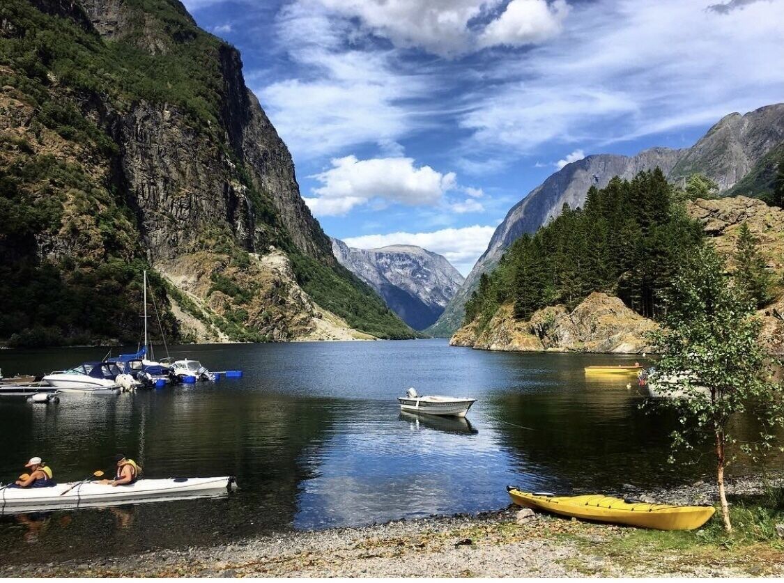 A calm lake surrounded by mountains, with boats docked at the shore.