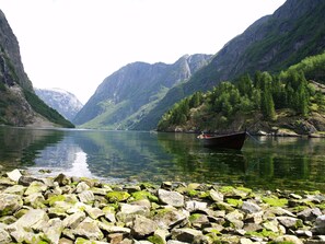 Ein Boot auf einem ruhigen Fluss, umgeben von felsigen Ufern und steilen Bergen.
