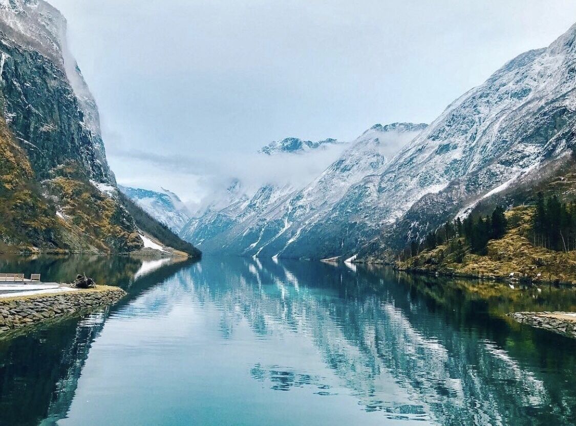 Ein ruhiger Bergsee mit einer Bank und einer felsigen Uferlinie.