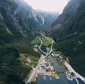 Vue aérienne d’une vallée avec une rivière, un pont et un petit village composé de bâtiments et d’un port de plaisance.