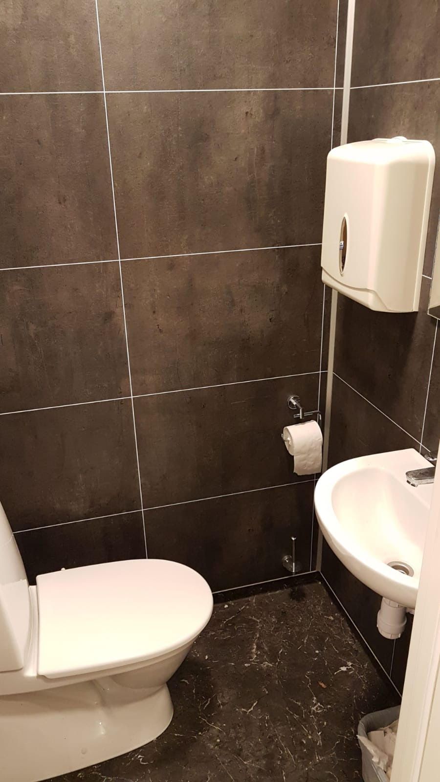 Un bagno con il water, un lavandino e un asciugatore di mani.