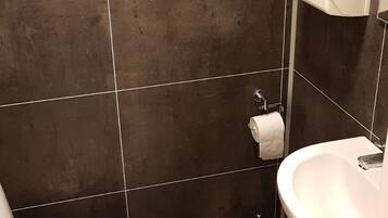 Un bagno con il water, un lavandino e un asciugatore di mani.