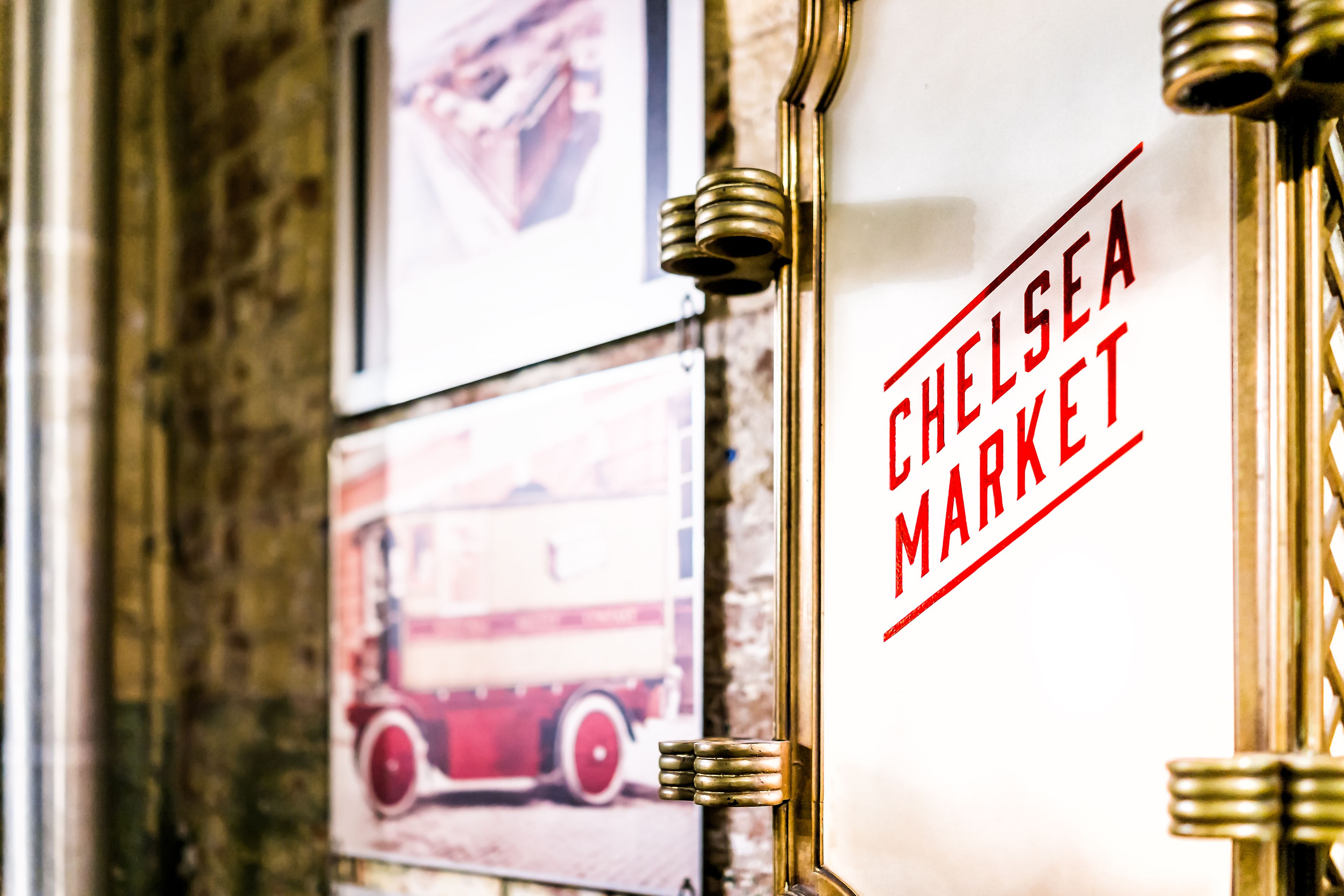 A framed picture of a red fire engine, a framed picture of a hand, and a sign with "CHELSEA MARKET" written on it.