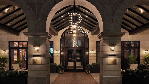 A hotel entrance with a large arched doorway, illuminated by a series of lights forming a pattern.