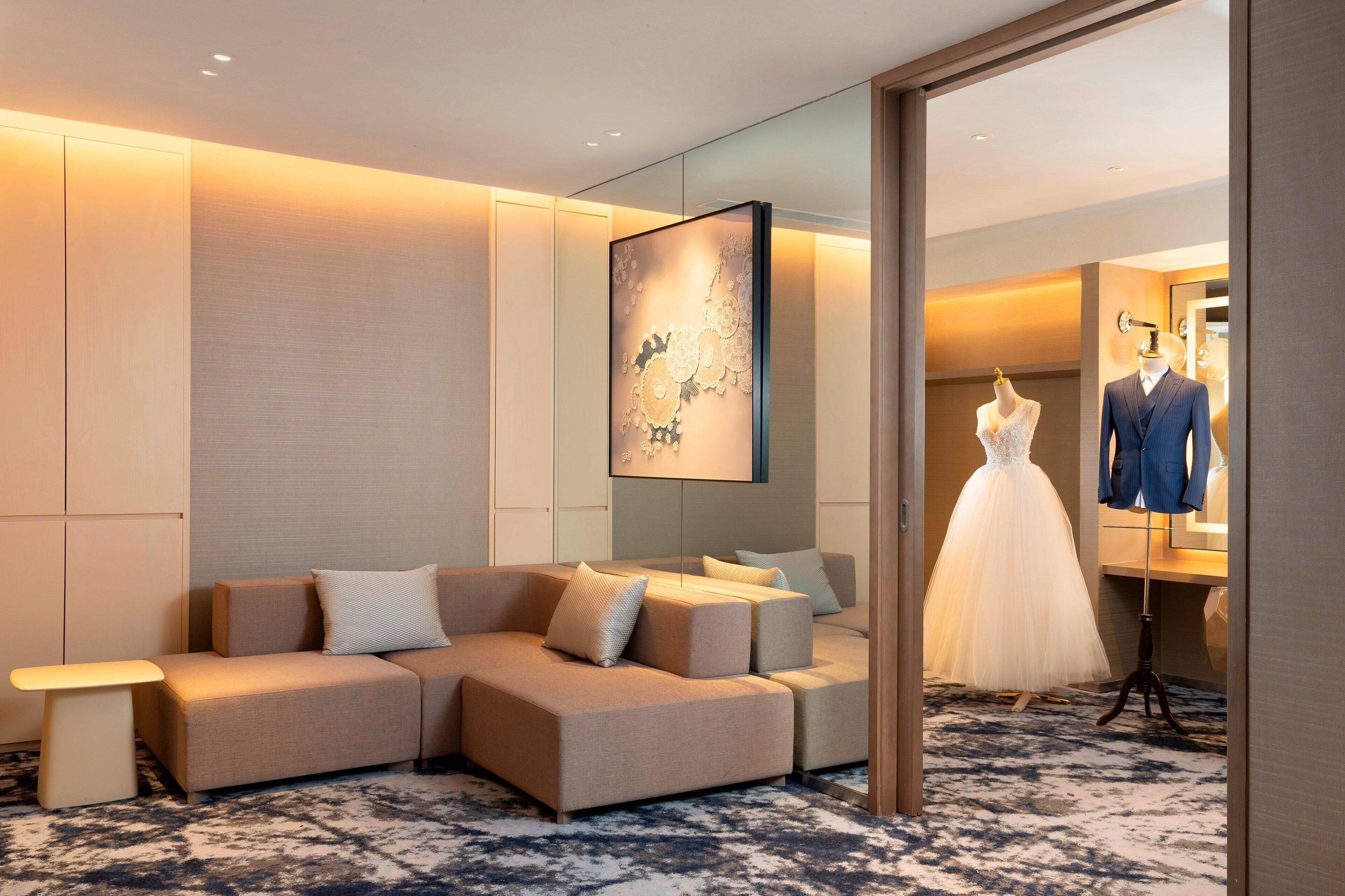 Una habitación de hotel moderna con un sofá seccional, un maniquí y un espejo.