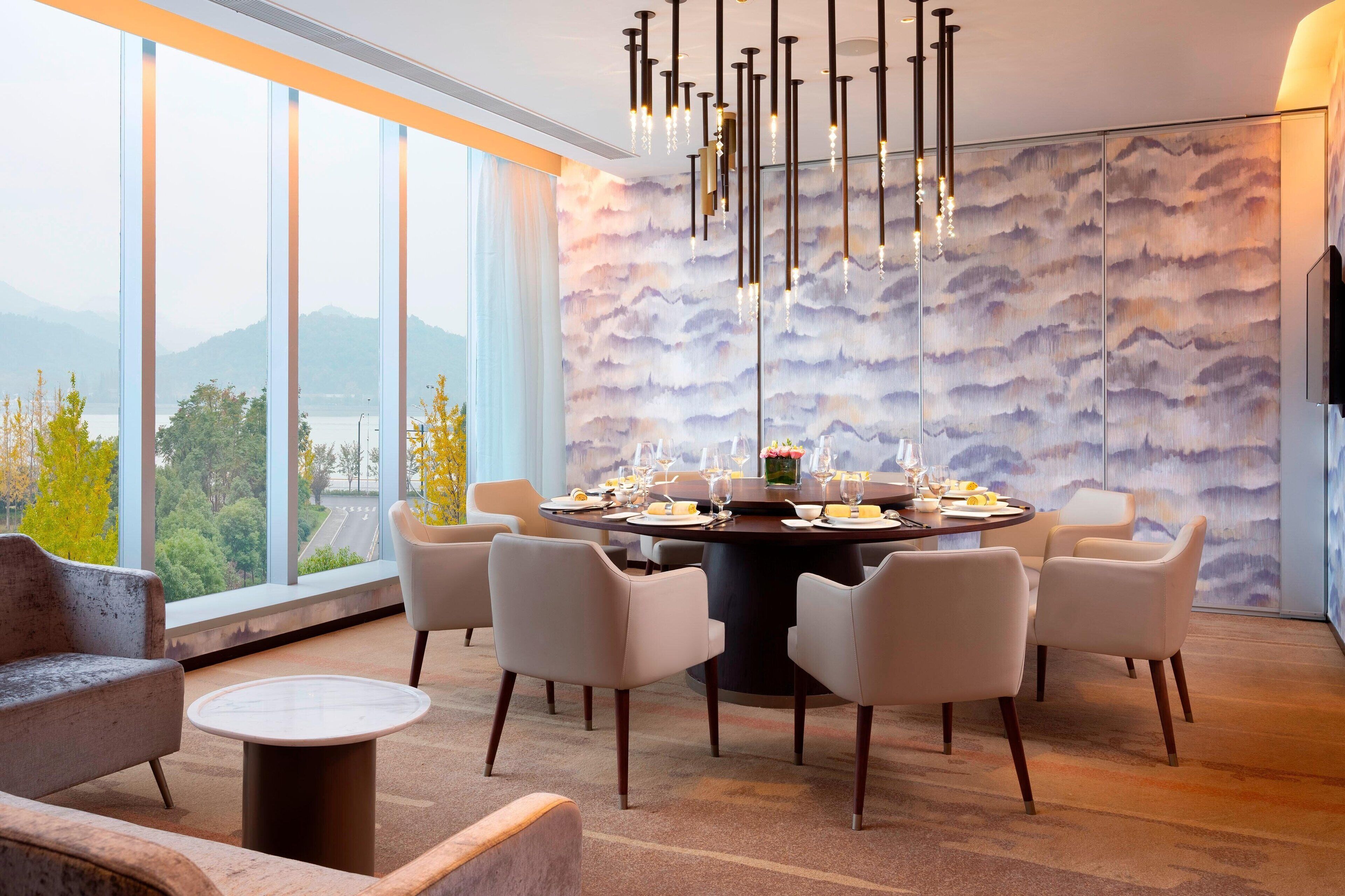 A modern dining area with a round table set for six, surrounded by six chairs.