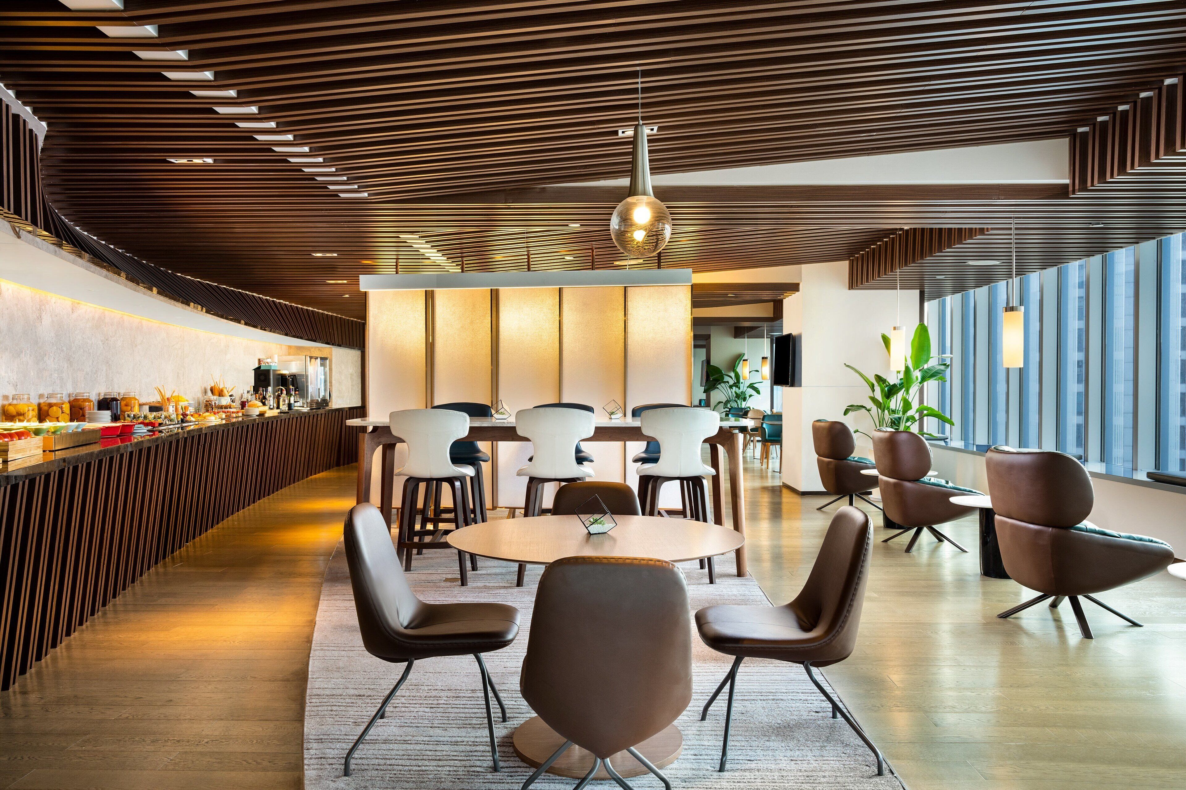 Un intérieur moderne avec un long comptoir, des tables rondes et des chaises contemporaines.