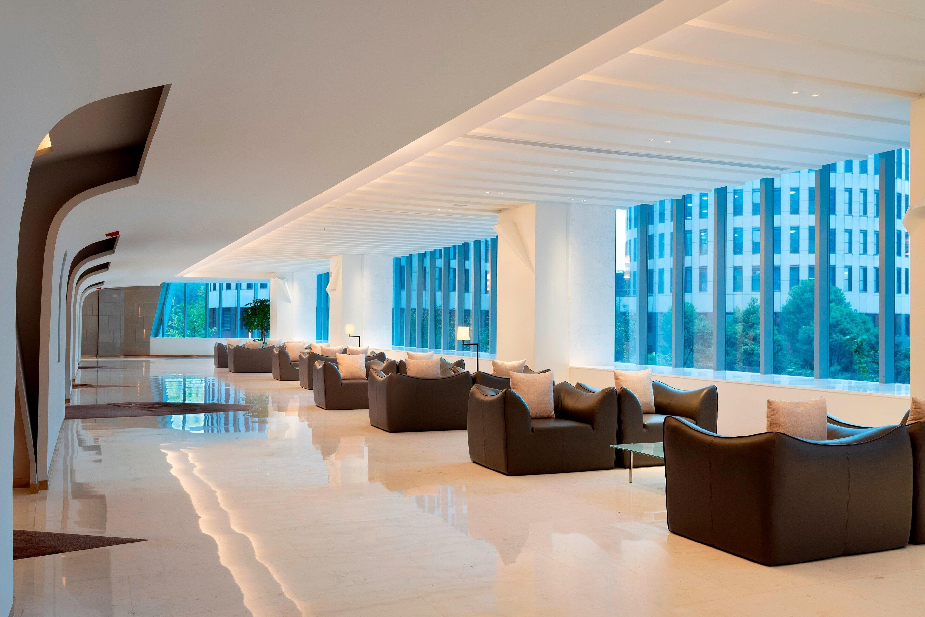 A spacious lobby with modern sofas and large windows offering views of the city.