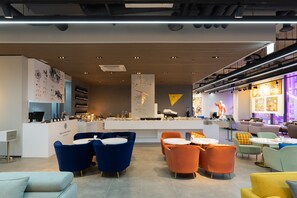 Un moderno vestíbulo de hotel con mostrador de recepción, zonas de estar y un bar.