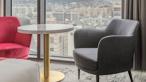 Een moderne hotelkamer met een groot raam, een ronde tafel en twee stoelen.