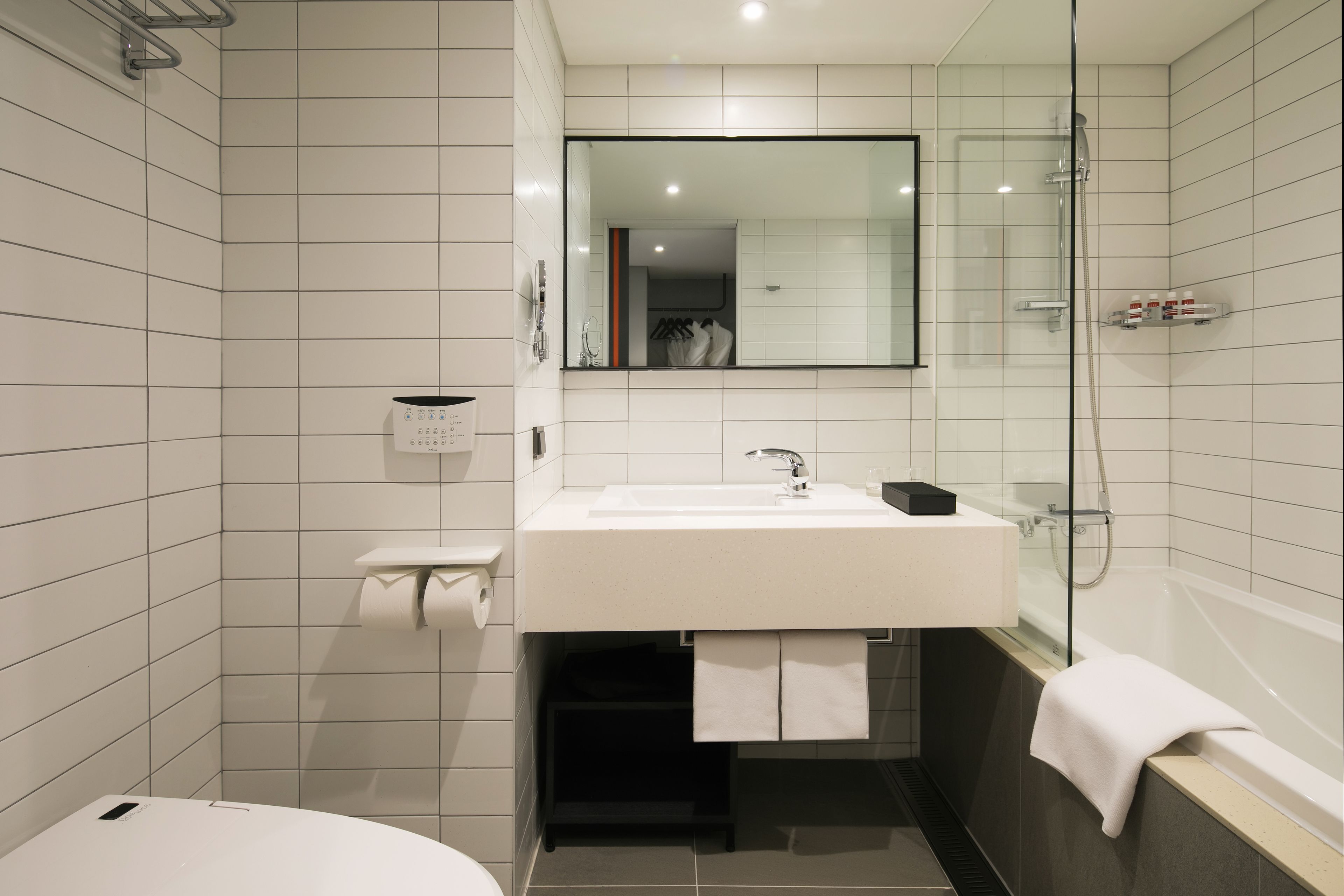 Un baño moderno con un lavabo, espejo y ducha blancos.