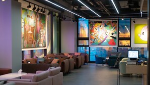 Een moderne lounge met banken, fauteuils, een receptiebalie en kleurrijke kunst aan de wanden.