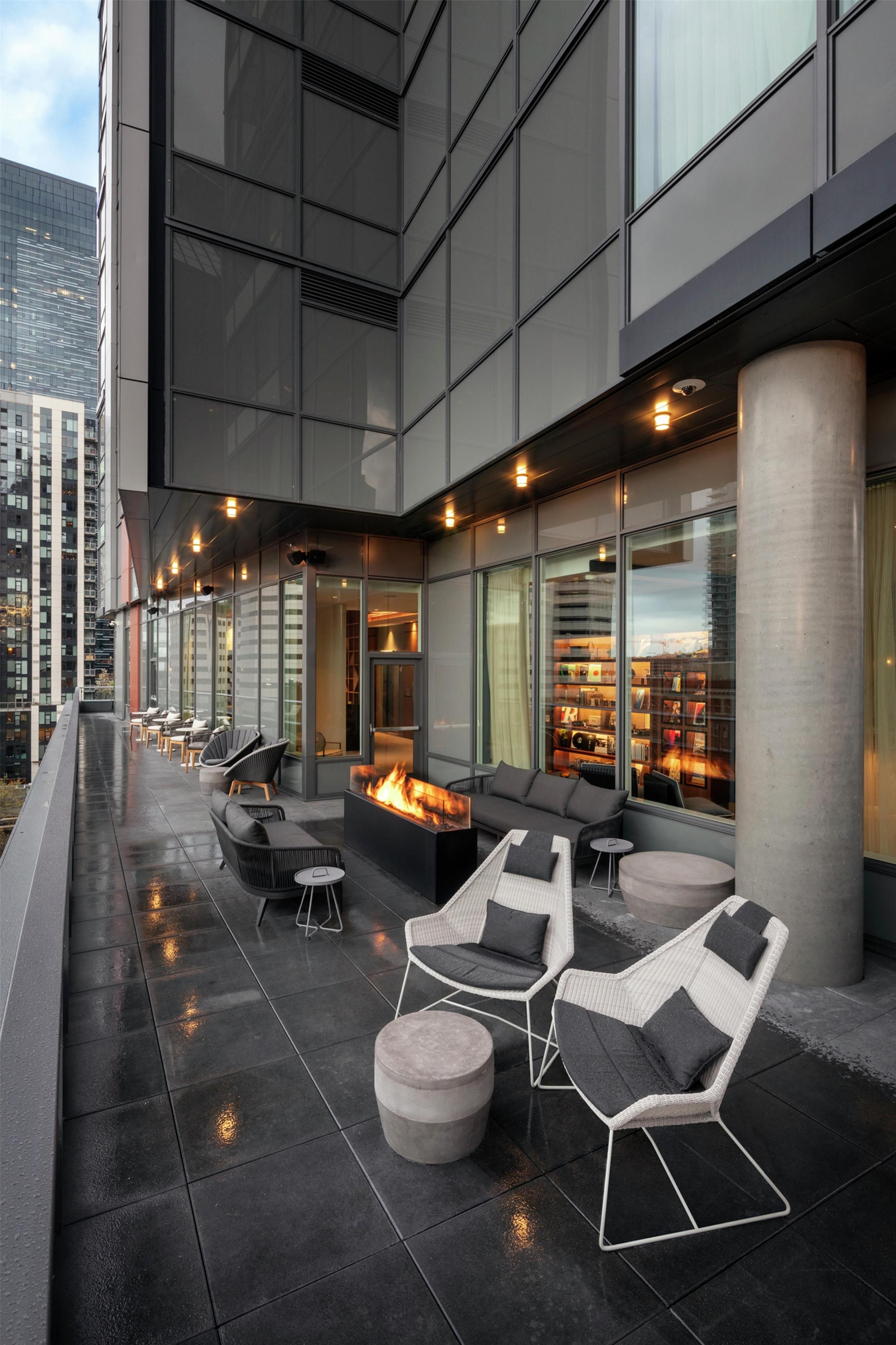 Una terraza en la azotea con mobiliario exterior, una chimenea y vistas a la ciudad.