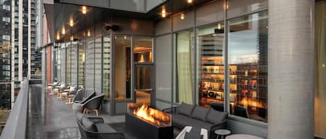 A rooftop terrace with outdoor seating, a fire feature, and a view of the cityscape.