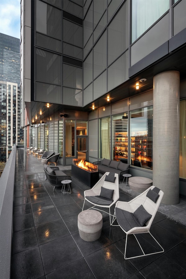 A rooftop terrace with outdoor seating, a fire feature, and a view of the cityscape.