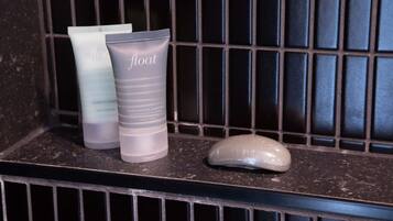 Une étagère de salle de bain avec trois flacons de produits de toilette étiquetés « flottant » et un savon.