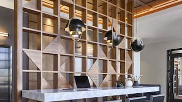 Un comedor moderno con una mesa de mármol, sillas negras y una estantería de madera con lámparas colgantes.