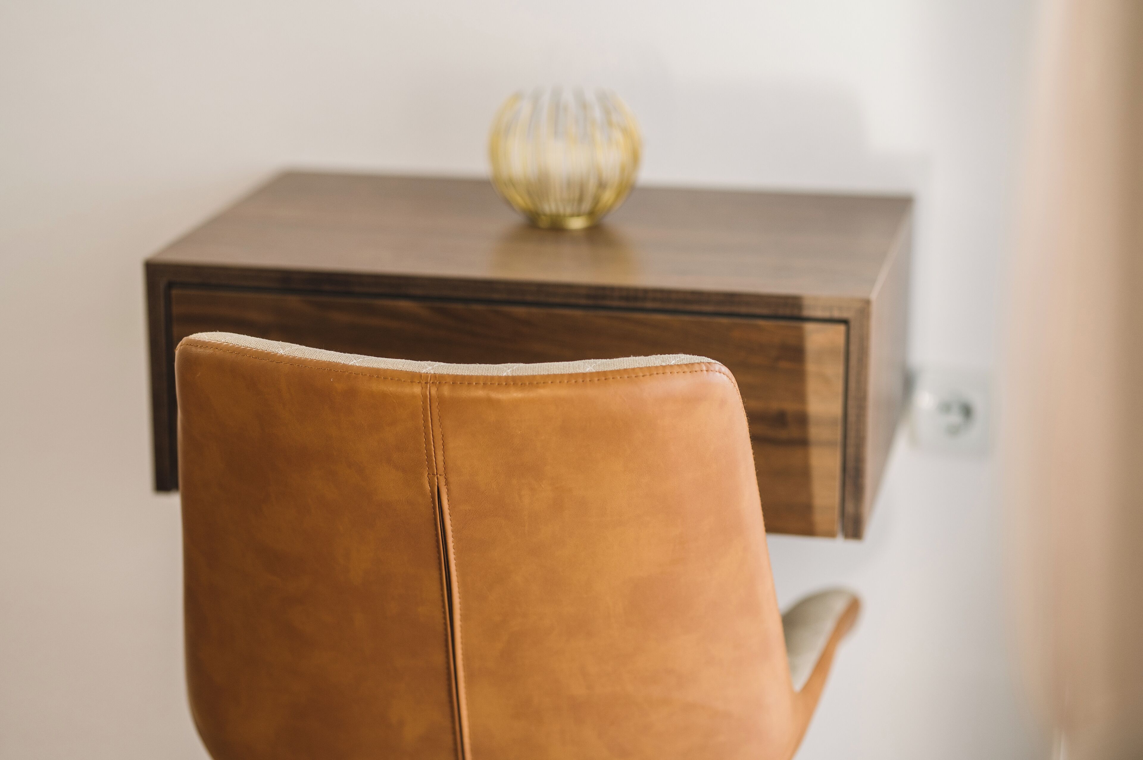 Een bruine lederen stoel gericht op een houten tafel met een decoratief glazen object erop.