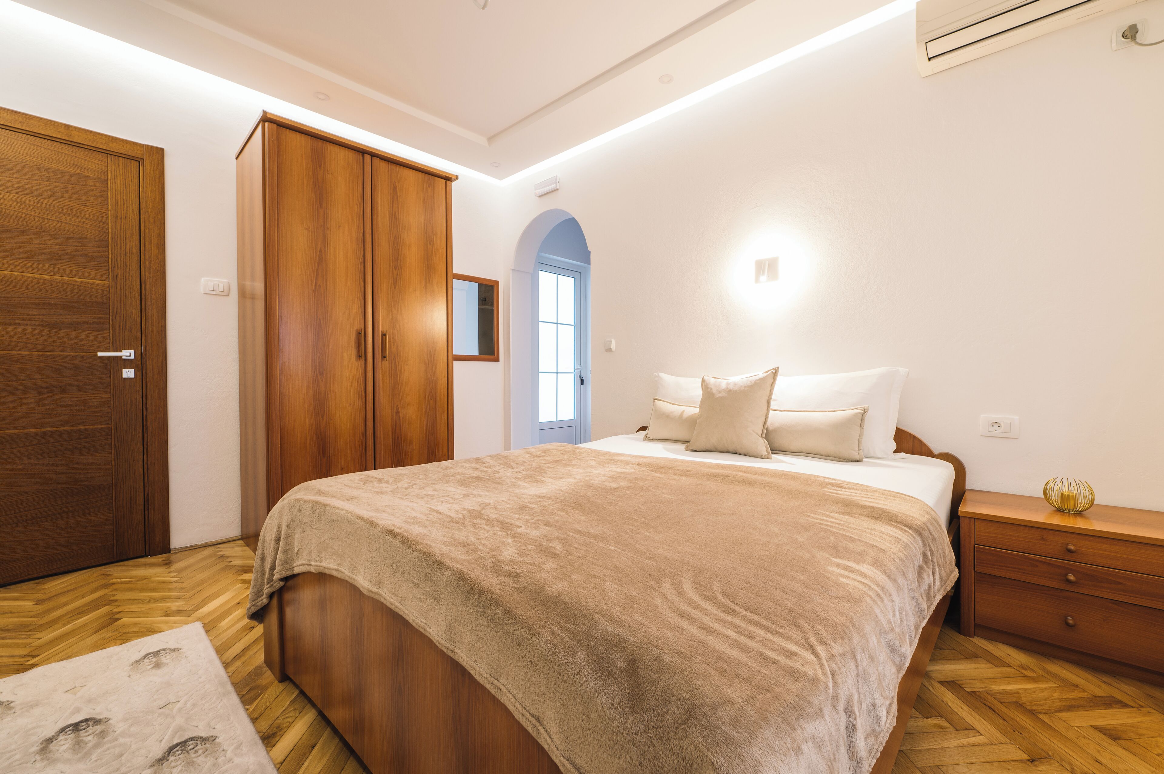 Un dormitorio con una cama grande, un armario de madera y una mesita de noche con una lámpara.