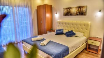 A bedroom with a large bed, a wardrobe, a bedside table, and a painting on the wall.