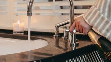 A bathroom with a modern faucet, a checkered sink backsplash, and a lit candle.