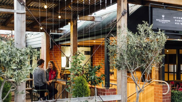 An outdoor seating area with brick walls, wooden beams, and hanging lights.