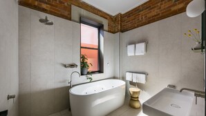A modern bathroom with a freestanding bathtub, a sink, and a window with a view.