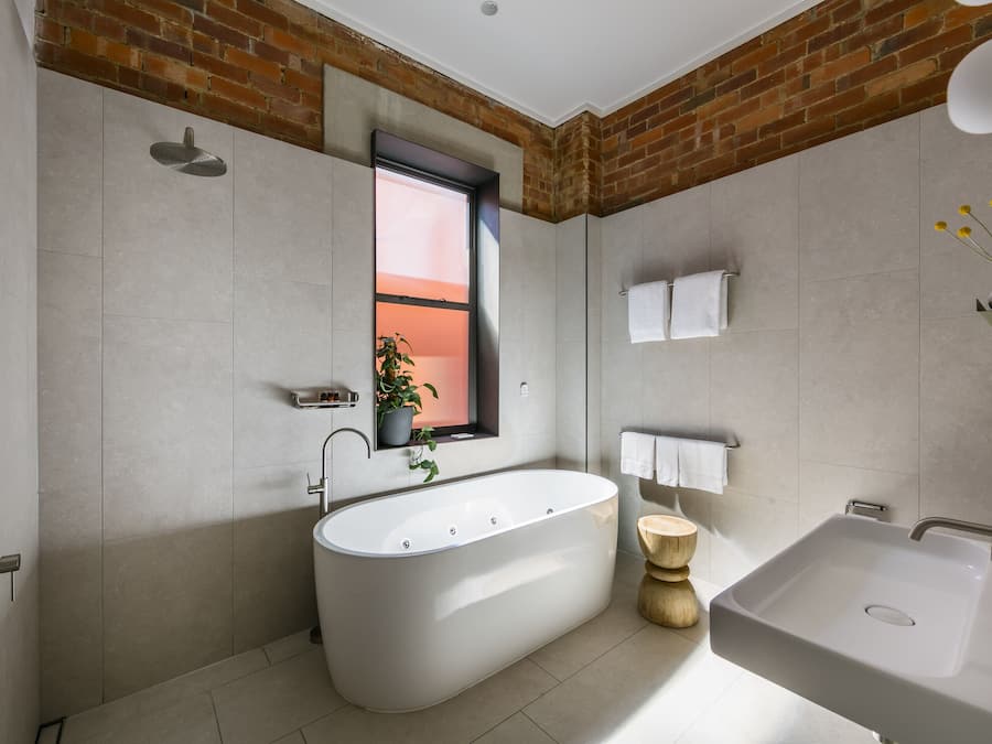 A modern bathroom with a freestanding bathtub, a sink, and a window with a view.